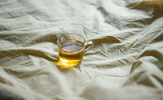 High angle view of hot tea on the bed sheets.