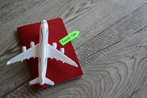 Toy plane and passport with text TRAVEL TIPS. Travel and transportation concept