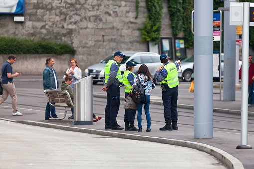 Zurich, Switzerland - June 13 2018: Three Police officers from the Polizei Assistenz discussing at a tramway station.