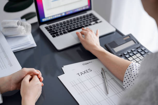 istock Woman accountant using a calculator and laptop computer while counting taxes for a client. Business audit and finance concepts 1474169867