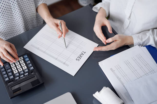istock Woman accountant using a calculator and laptop computer while counting taxes for a client. Business audit and finance concepts 1474169870