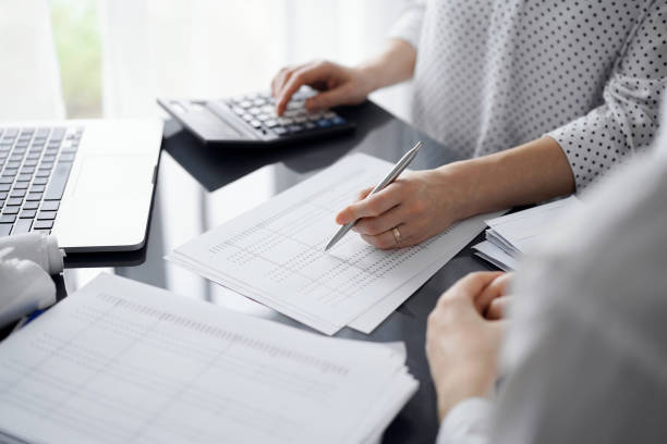 istock Woman accountant using a calculator and laptop computer while counting taxes for a client. Business audit and finance concepts 1474169899