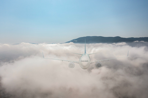 Commercial Jet airplane flying over clouds.