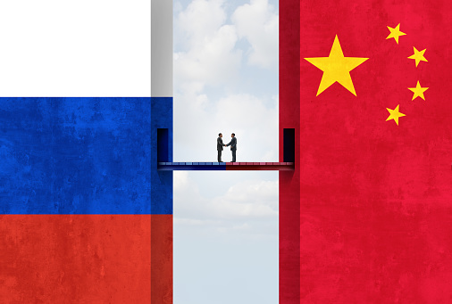 Hand holding Russia and China flags on puzzle pieces joining together