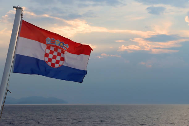 Flag of Croatia on the boat, blowing in the wind. Sea and sunset sky in the background. Selective focus.