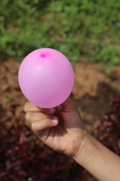 istock Small Pink Baloon on a Little Hand With Nature Background 1474177646