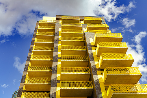 Futuristic design of high rise apartment buildings in the Docklands area of London, UK. The buildings are decorated with bright colors such as yellow and orange.