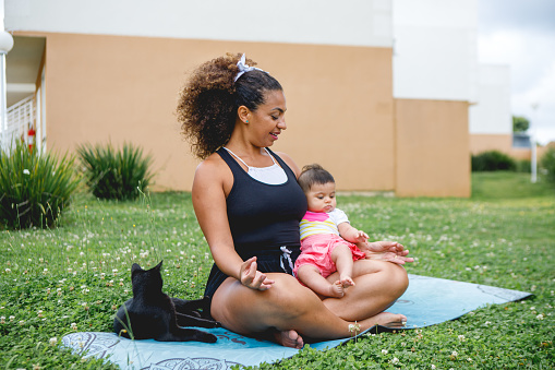 brazilian woman doing meditation and yoga together with her baby daughter