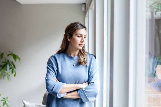 Serious woman, deep in thought, looks out window