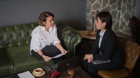 Two businesswomen are meeting in a cafe and talking with each other.