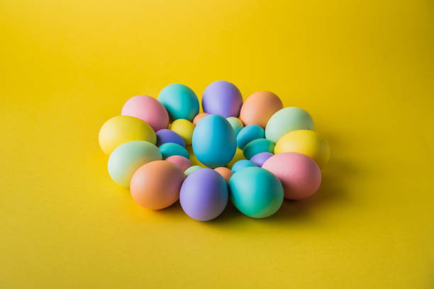 istock Colorful Easter eggs lying down and a leader standing on a yellow background. 1474184003