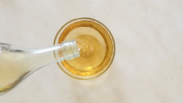 apple cider vinegar is poured from the bottle into a glass bowl
