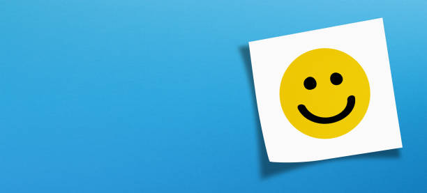 istock Happy smiley face emoticon with white note paper on blue background 1474184057