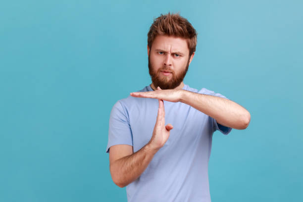 Man showes time out gesture looking with imploring eyes hurry to meet deadline begging for more time stock photo
