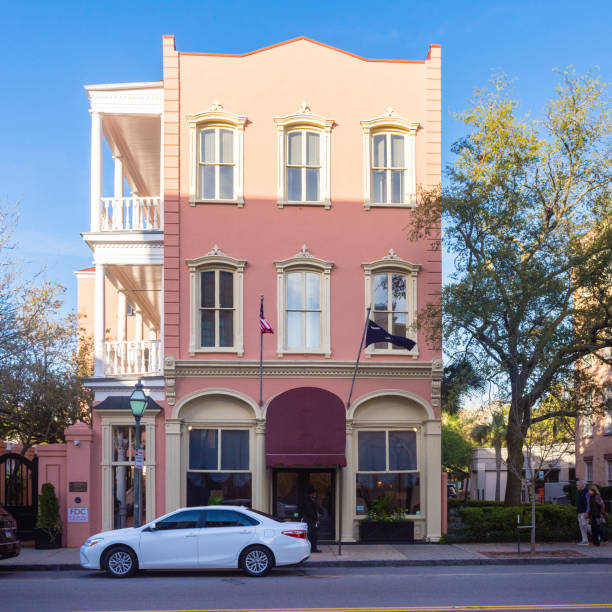 Three story colorful building on Meeting Street in the French Quarter of Charleston illuminated by early morning sun. stock photo