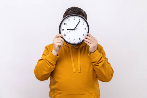 istock Unknown man hiding face behind big wall clock, time management, reminding of deadline. 1474185231