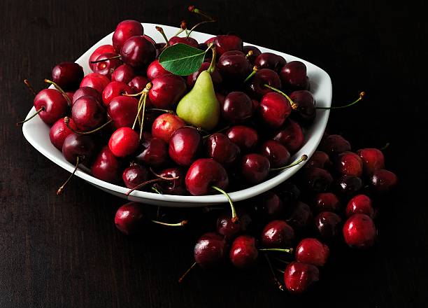 small pear on a plate of cherries stock photo