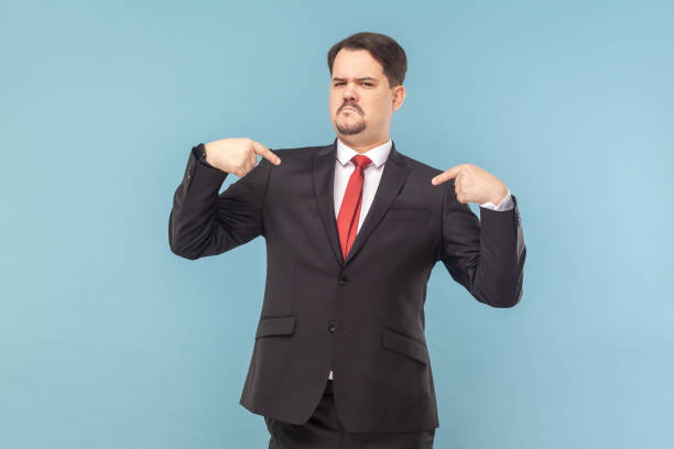 Bossy confident man pointing at himself with both index fingers looking at camera with frowning face stock photo