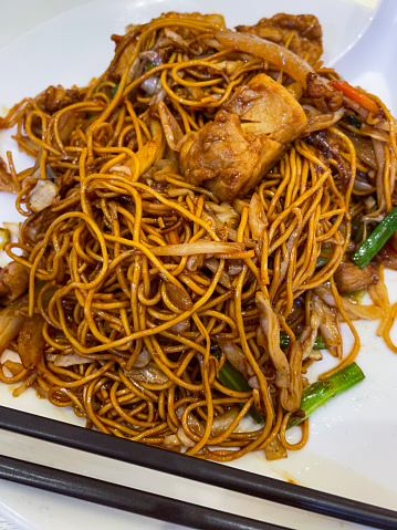 Stock photo showing a popular Chinese takeaway dish of chicken chow mein. This tasty stir-fried chicken dish comprises chicken breast, bean sprouts, sliced spring onions, soy sauce, black pepper, five-spice, sesame oil, cornstarch (cornflour) and egg noodles.