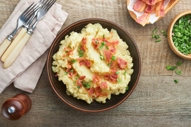 istock Mashed potatoes. Bacon mashed potatoes with green onion, pepper and cheddar cheese in bowl on old wooden backgrounds. Delicious creamy mashed potatoes. Top view. 1474187762