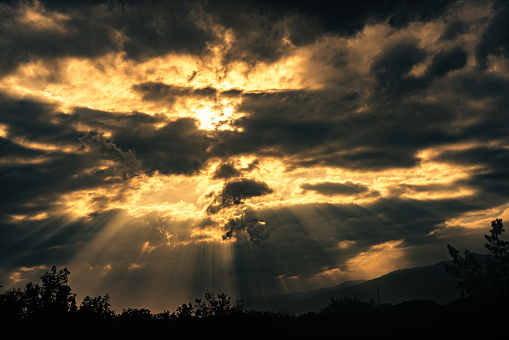 A breathtaking view of the sky, the ever-changing cloud formation in the sky, with the sunlight shining through the gaps, creating beautiful rays of light known as crepuscular rays or \