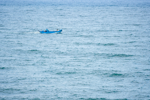 A blue fishing boat navigating through the waves on the open sea.