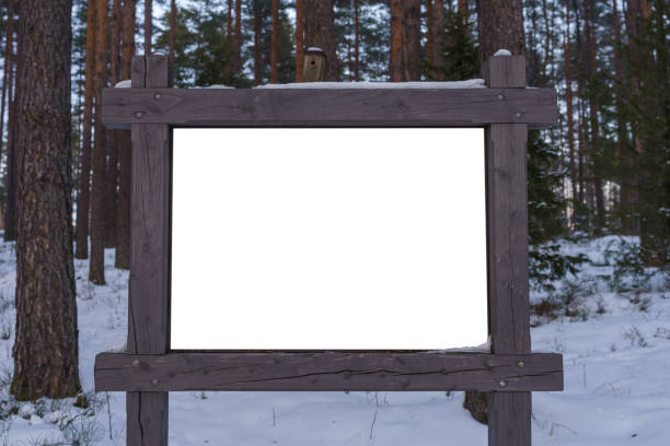White empty billboard with a wooden frame in the forest in winter.