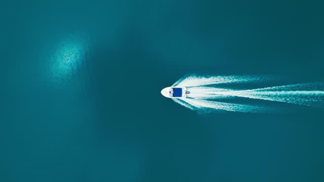Drone shot of motorboat in open blue water on wave
