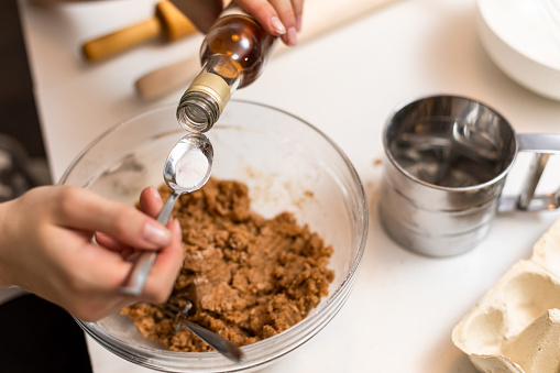 The process of quenching the vinegar in a teaspoon over the dough. The process of making cookies at home.