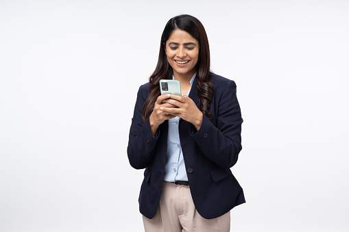 Portrait of young female entrepreneur with cellphone working online or chatting on white background