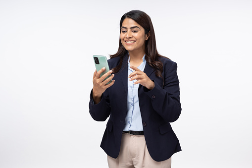 Portrait of young female entrepreneur with cellphone working online or chatting on white background