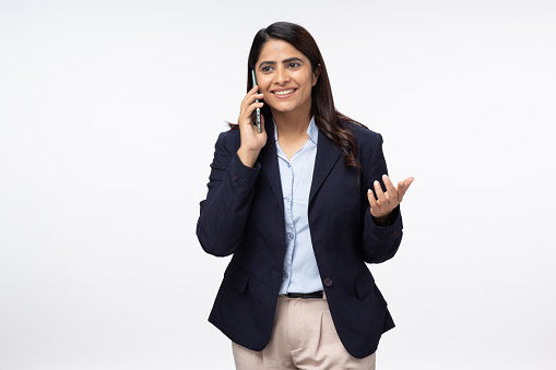 Portrait of happy young female on white background talking on smart phone