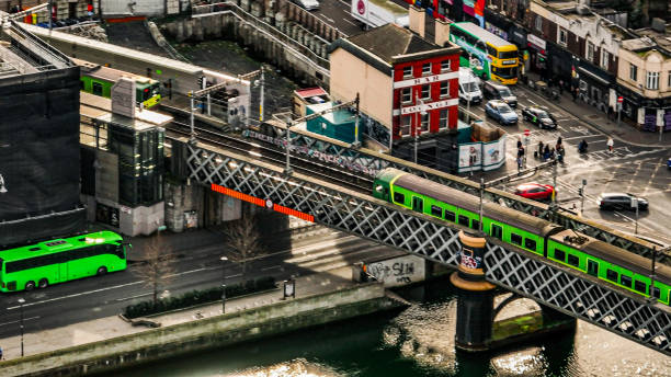 vista aérea do trem dart verde em dublin irlanda, vista aérea do trem / bonde cruzando a ponte, vista aérea do trem no centro da cidade, trem sobre a ponte do rio no centro da cidade, trem na ponte de bunda dublin, transporte público no centro da cidad - dublin ireland custom house famous place republic of ireland - fotografias e filmes do acervo