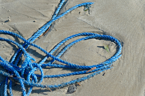 Plastic pollution. Discarded nylon rope on the beach
