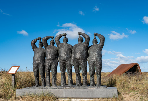 Katwijk aan Zee, The Netherlands, 26.02.2023, Artwork of dutch men eating herring against blue sky at seaside resort Katwijk aan Zee