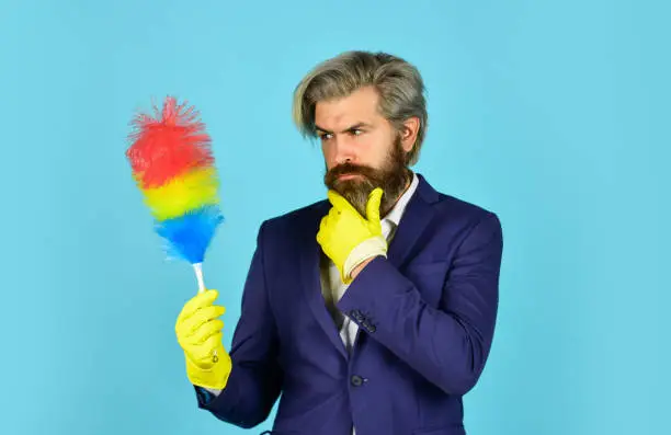 Photo of Office duster. Man use pp duster. Dust allergy. Businessman cleaning office. Cleaning service. Housekeeping duties. Cleaning apartment. Clear reputation. Hipster hold cleaning tool. Cleaning concept