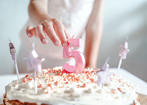 Big pink 5 number candle on homemade cake. Creative congratulations on five years for child girl. Festive decoration for 5th birthday, topping, dressing. Merry home holiday, party with mom, family.