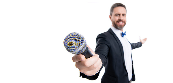 presenter man with microphone, copy space. man presenter wear tuxedo in studio. presenter man speaking in microphone. man presenter isolated on white background.