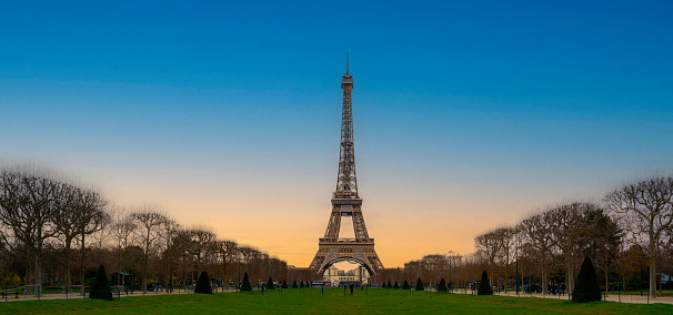 The Eiffel Tower over the green lawn field of Champ de Mars, Field of Mars, in Paris, France