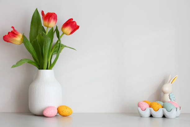 istock Happy Easter composition. Table with vase of tulips, colorful Easter eggs, decorative bunny. 1474209965