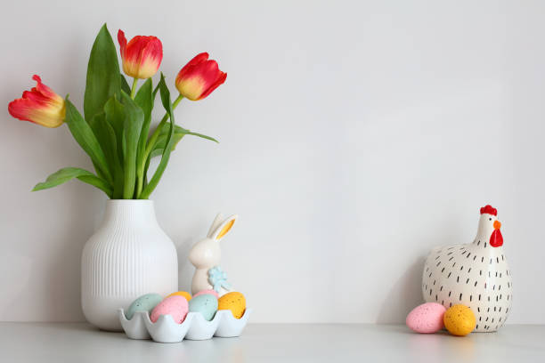 Happy Easter home decor. Table with vase of tulips, colorful Easter eggs, decorative bunny and chicken. stock photo