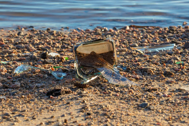 istock Broken glass bottle on the shore - environmental pollution 1474214713