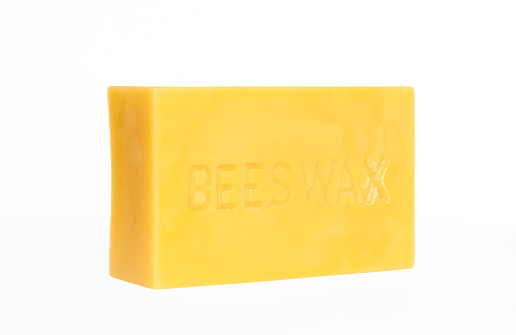 An angled view of a brick of beeswax on a white background