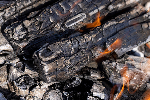 several burning logs in close-up, kindling a fire made of wood during outdoor recreation
