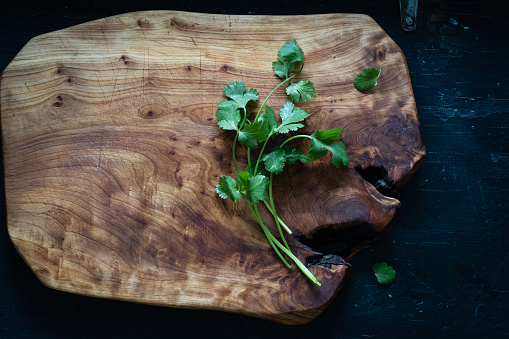 Sprigs of fresh cilantro on a rustic wooden cutting board.