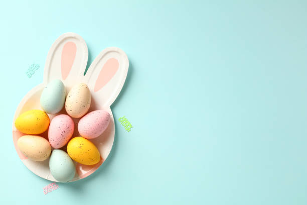istock Bunny shaped plate with colorful Easter eggs on blue background. Happy Easter greeting card design. 1474222492