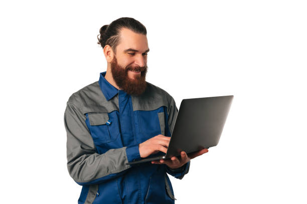 istock Smiling bearded man wearing engineer uniform is working on the laptop. 1474225439