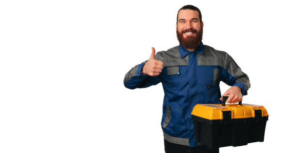 istock Bearded smiling handyman is holding a box full of tools and a thumb up. 1474225443