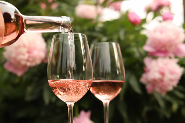 美しい牡丹に対してボトルからグラスにロゼワインを注ぐ、クローズアップ - drink alcohol summer celebration ストックフォトと画像