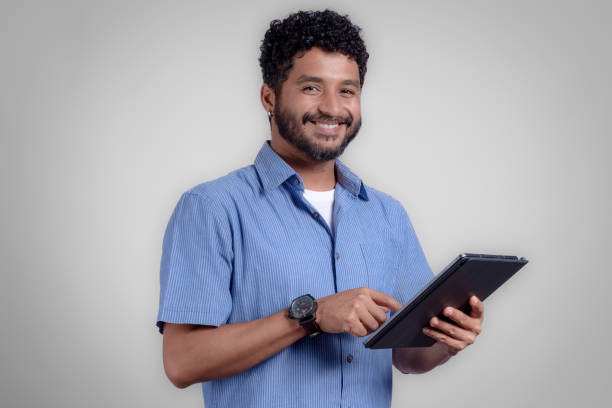 istock Portrait of young man from the side using digital trablet in studio with gray background 1474229461